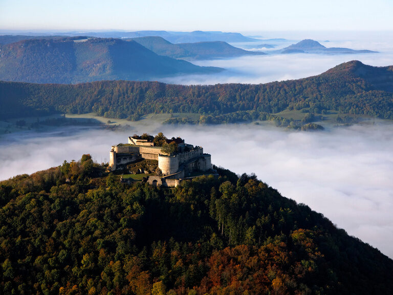 Ein majestätisches Schloss auf einem Berggipfel in der nebligen Landschaft der Schwäbischen Alb.
