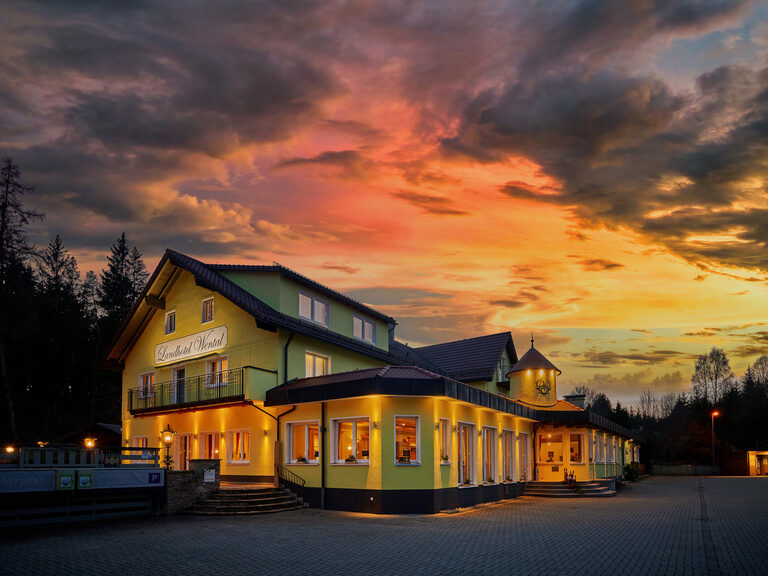 Der Himmel färbt sich orange hinter dem Hotelgebäude.