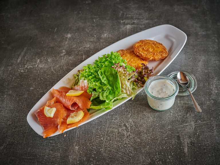 Ein kunstvolles Tellergericht mit Fisch und Gemüse auf feinem Geschirr.