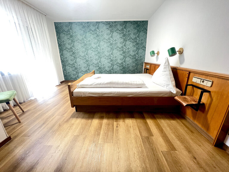 Das Hotelzimmer Tannenwald mit schöner Tapete und einem weichen Bett