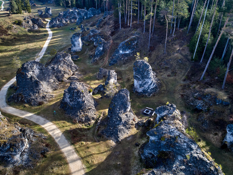 Ein dichter alter Wald mit markanten Gesteinsformationen inmitten der Landschaft.