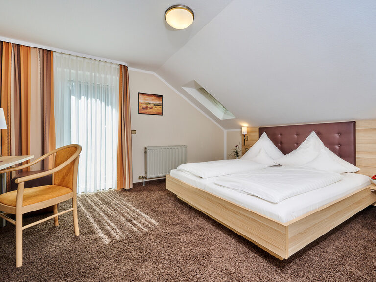 Ein komfortables Bett mit weicher Bettwäsche im Wanderlust Zimmer des Hotels.